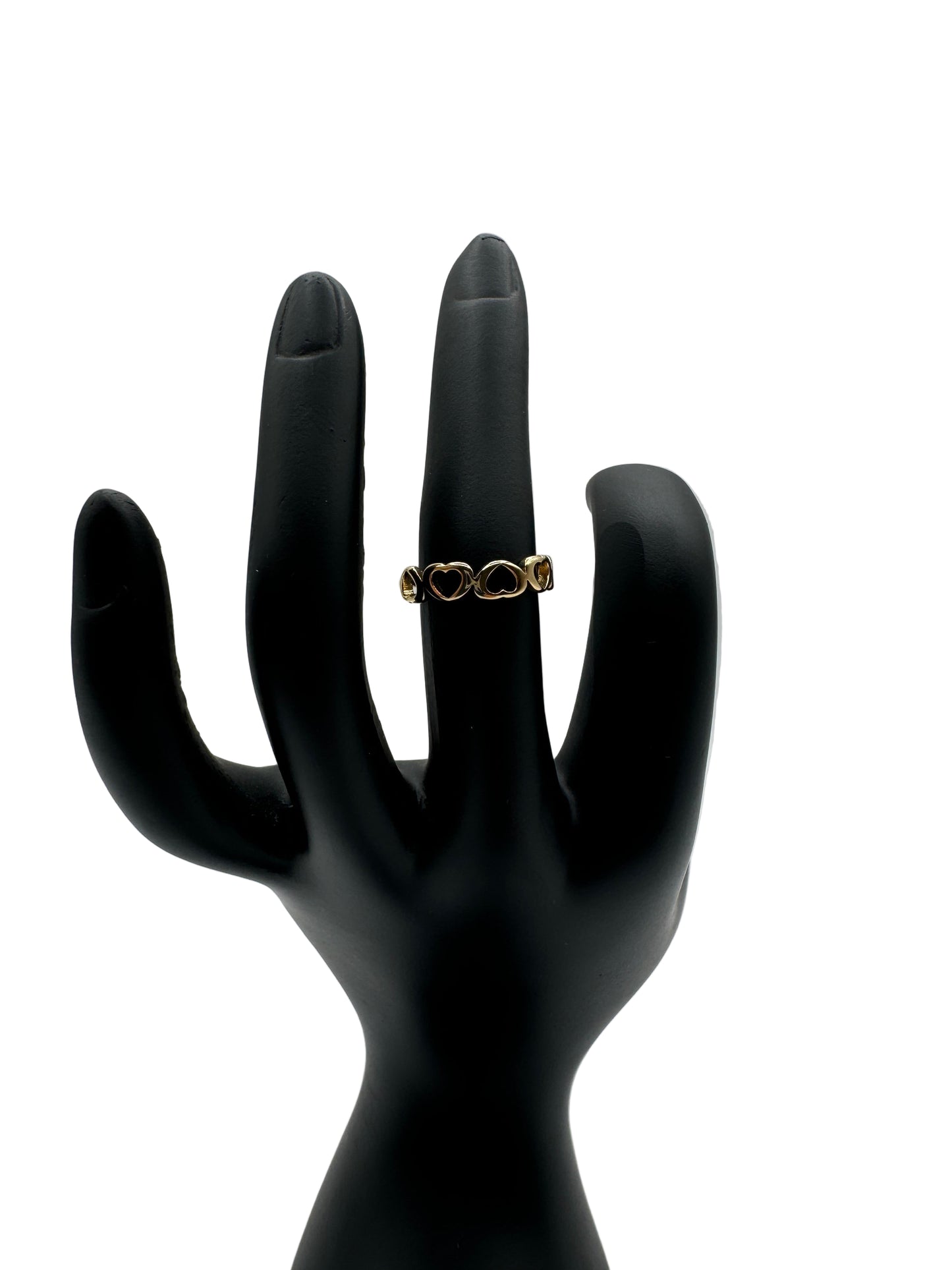 Gold ring on a black mannequin hand against a light gray background