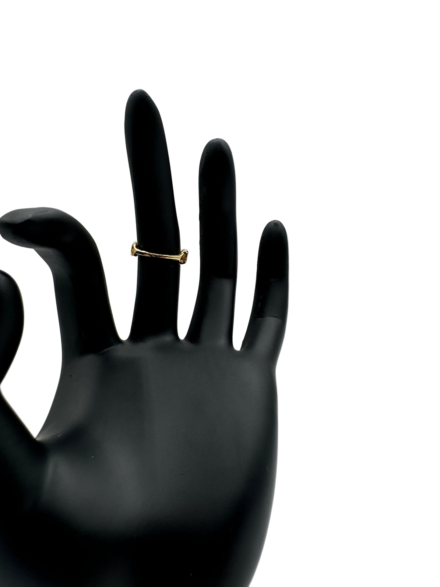 Gold ring on a black hand model against a gray background